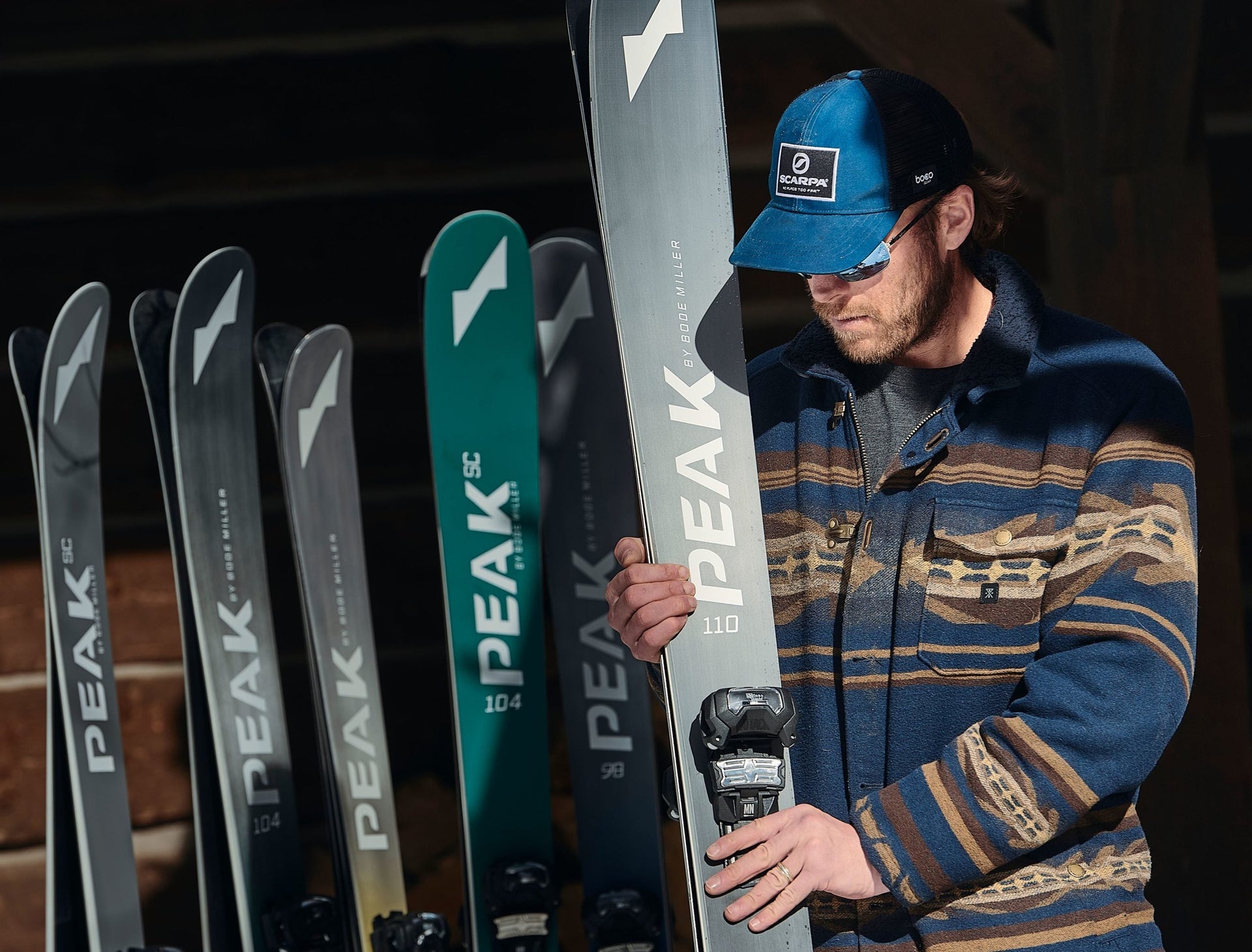 Bode Miller standing with sets of Peak Skis